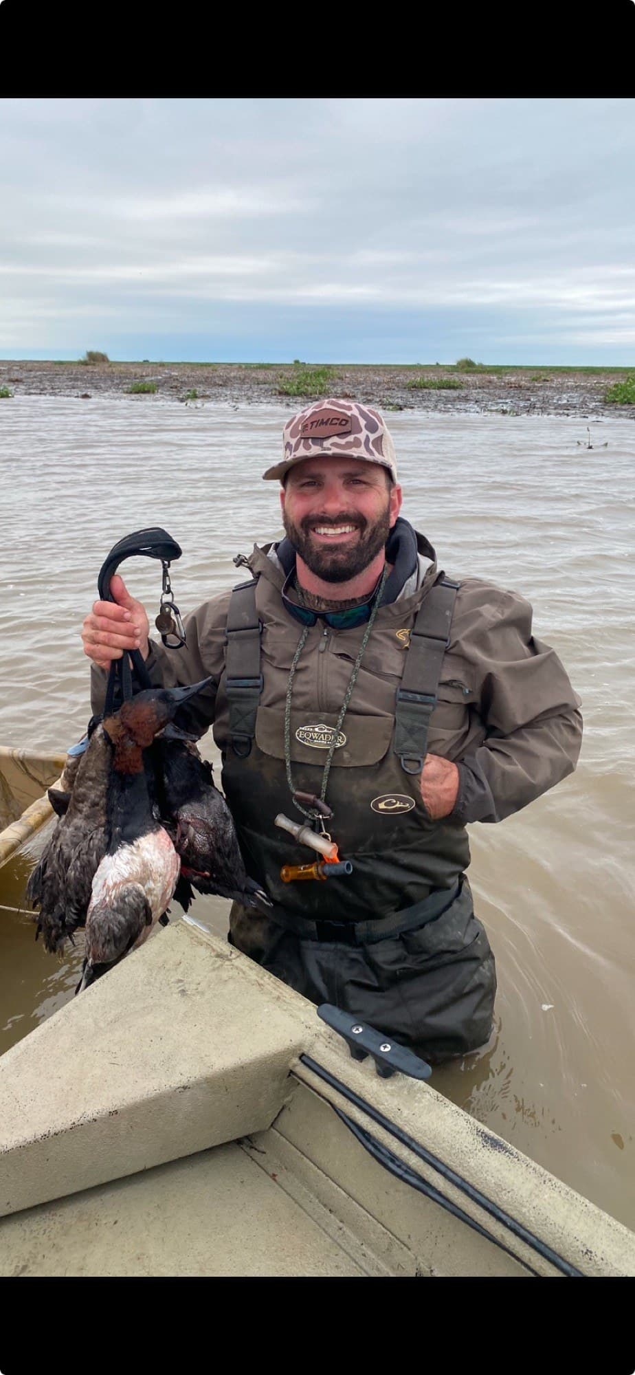 Timothy Caillouet, owner of TIMCO Kennels, in waders with a strap of ducks
